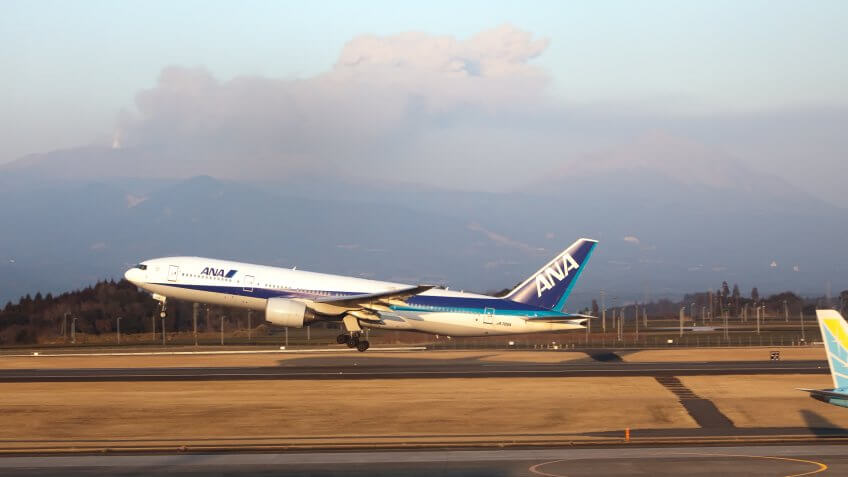 "Kagoshima, Japan - February 3, 2011: ANA airplane takes off with Shinmoedake volcano erupting in background.