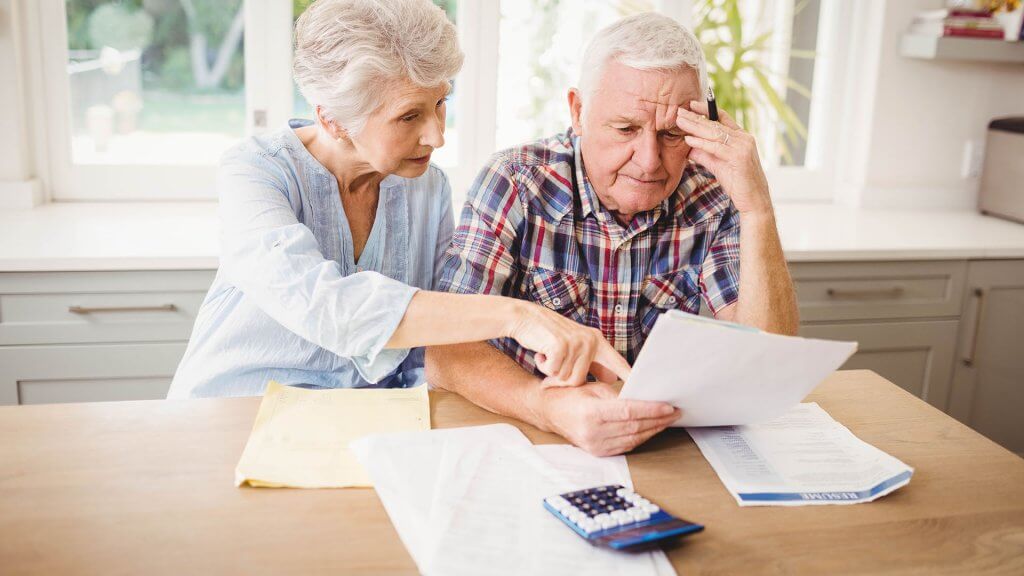 Withdrawing money too quickly in retirement. elderly couple looking over bills