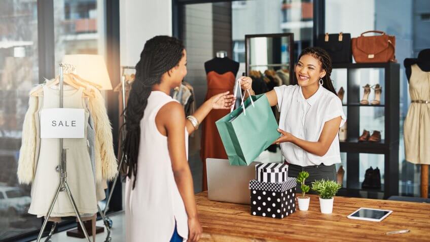 young store owner handing bag to a customer young store owner handing bag to a customer