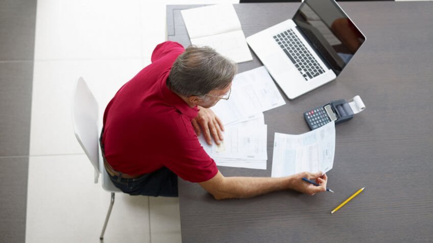 elderly man looking at document at desk