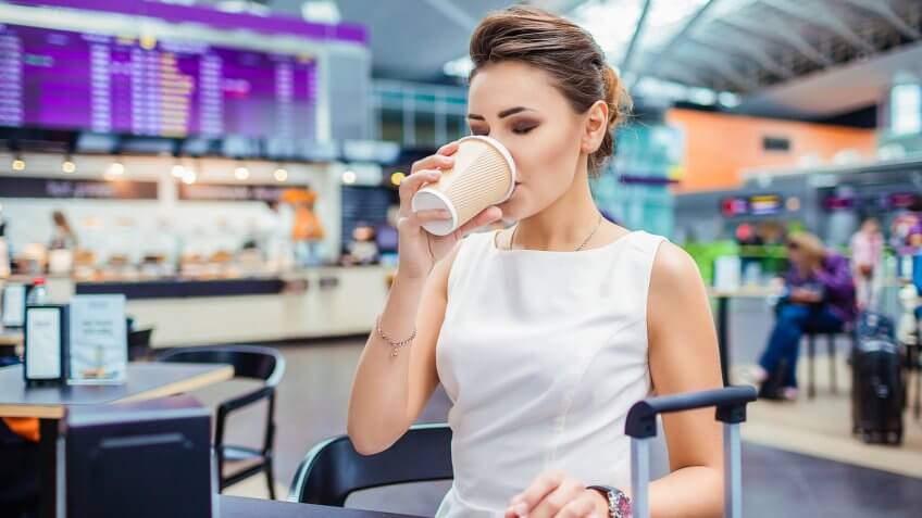 Woman sipping on coffee at airport cafe Woman sipping on coffee at airport cafe