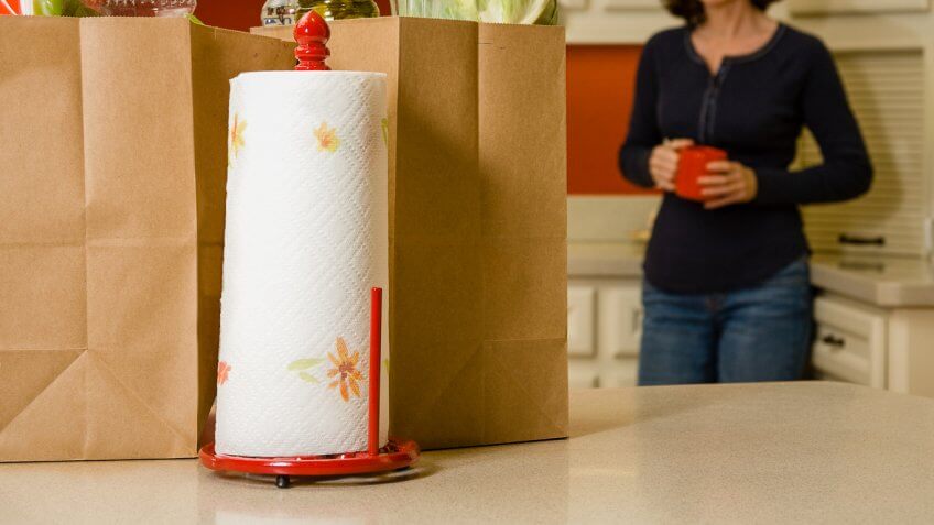 woman in kitchen with paper bags and paper towel roll on counter