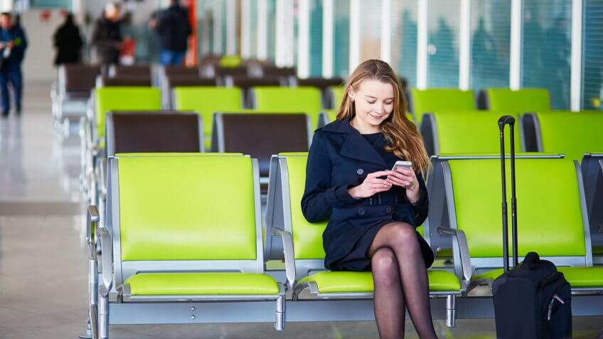 Woman sitting on airport chair checking phone Woman sitting on airport chair checking phone
