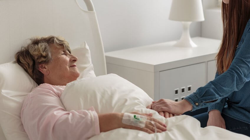 elderly woman in hospital bed with daughter or granddaughter by her side