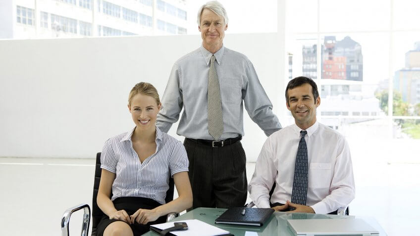 a businesswoman and businessman with presumably their boss standing behind them