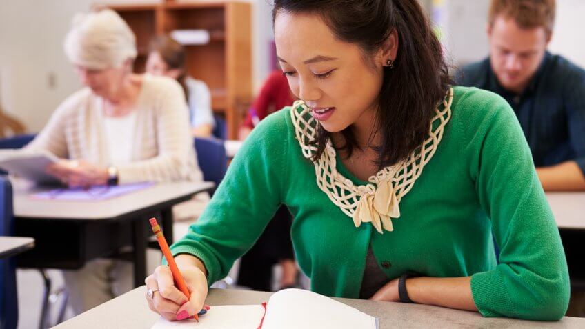 man writing in her notebook at a desk