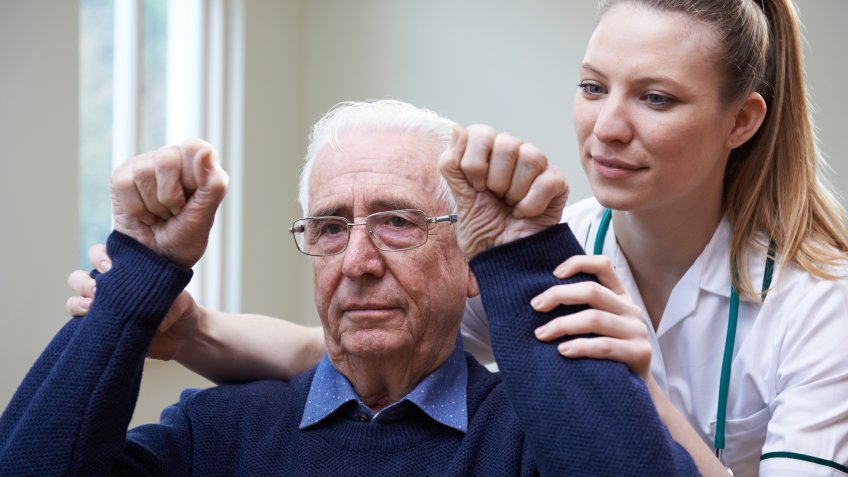 Nurse Assessing Stroke Victim By Raising Arms.
