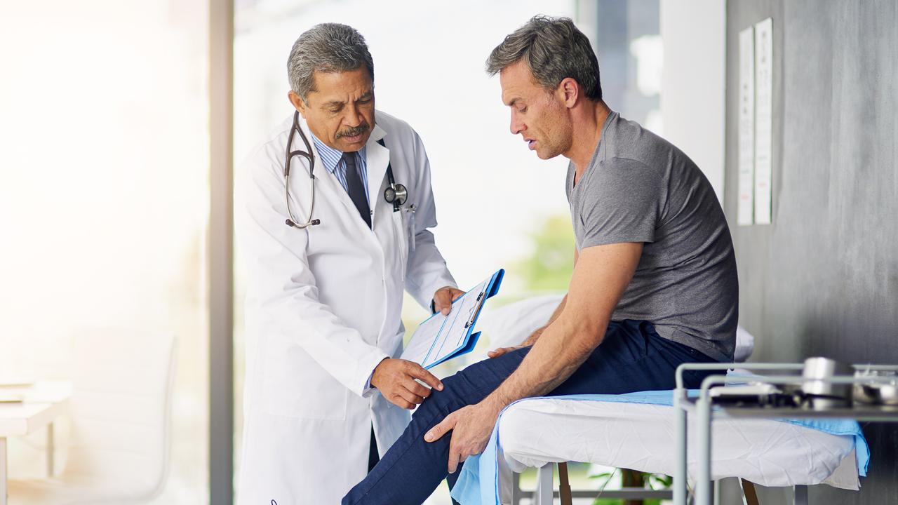 Shot of a mature doctor examining his patient who is concerned about his knee.
