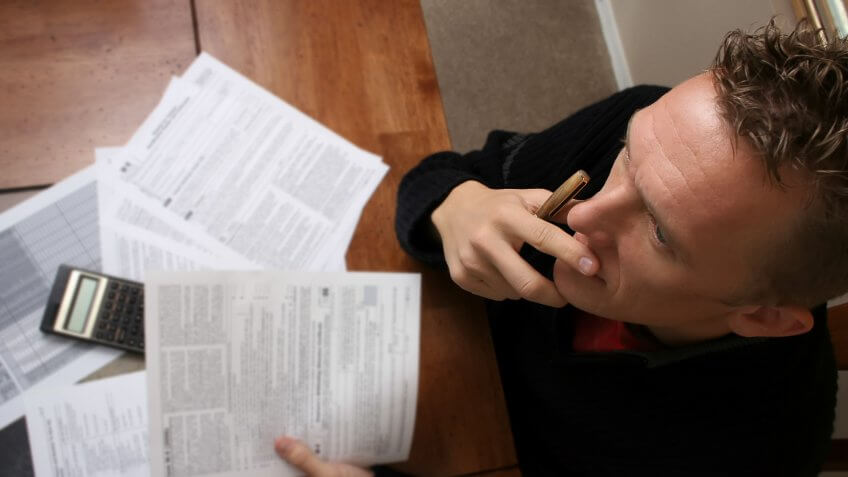 Young man contemplates his tax statements.
