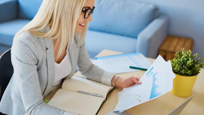 Consider Using Options Happy young woman working with financial data from home office.