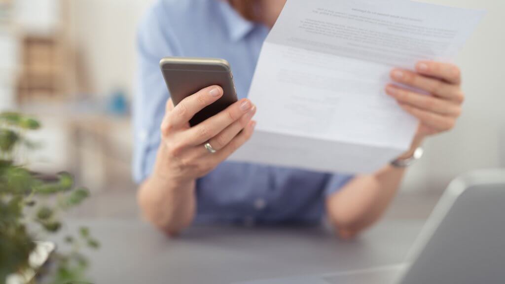 Plug Money Leaks woman holding bill and using phone