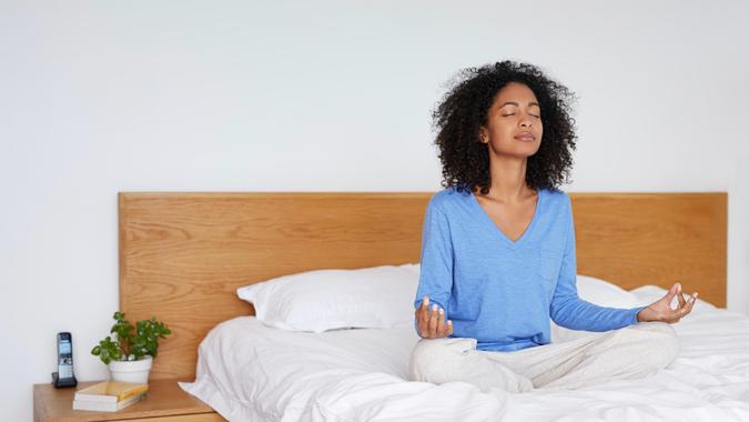 woman meditating on a bed