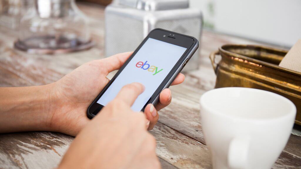 Sell Unused Items person using ebay on their phone