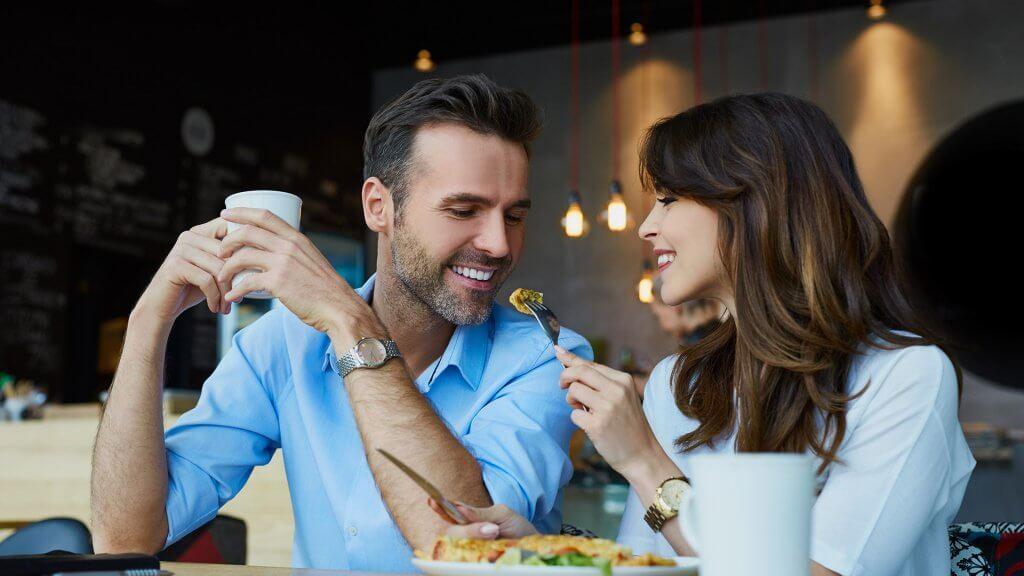 woman using fork to feed piece of food to boyfriend