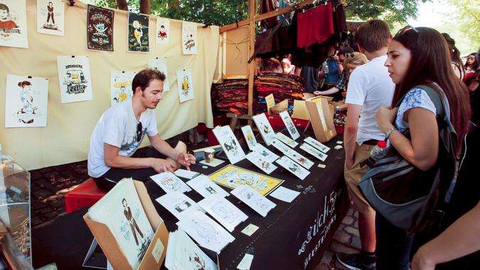 BERLIN, GERMANY - AUG 30, 2015: Young artist draws and sells graphic arts on street market in Mauerpark on August 30, 2015.