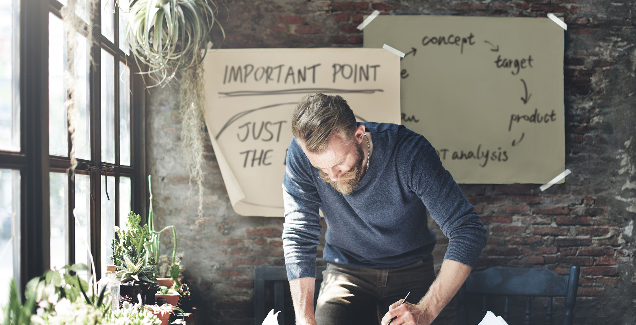Start a business man writing at desk near window with plants