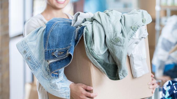 Unrecognizable woman holds a box of gently used clothing during community clothing drive.