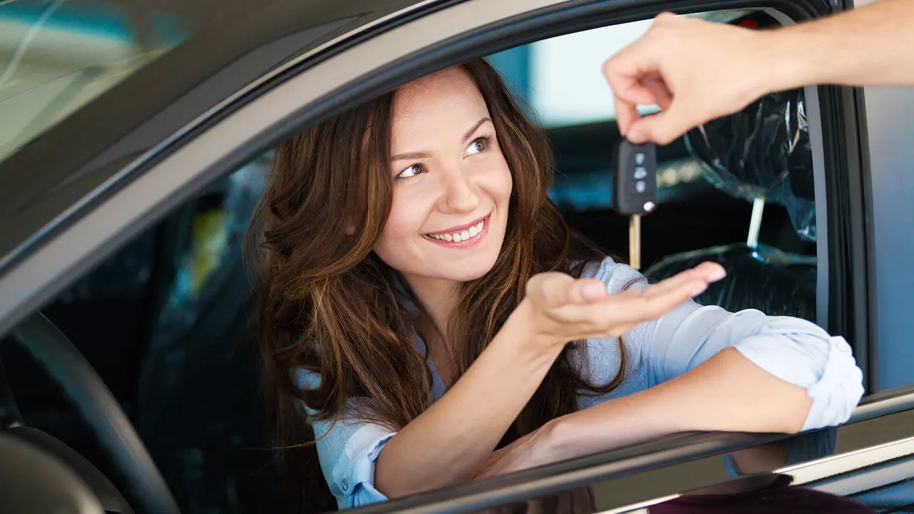 Woman having new car keys handed to her