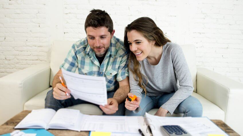 happy young couple reviewing documents on couch happy young couple reviewing documents on couch