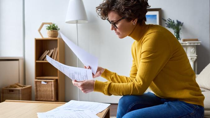 Concentrated woman reviewing financial documents at home.