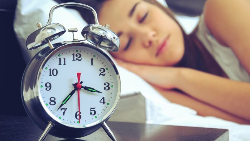 woman sleeping next to an alarm clock