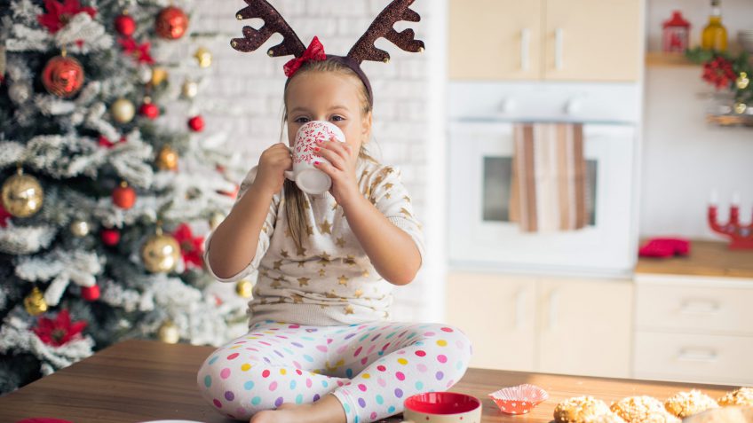 young girl drinking from a mug at Christmas