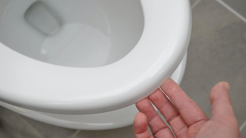 person lifting up toilet seat