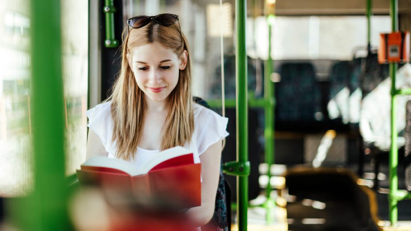 young woman reading on a public bus