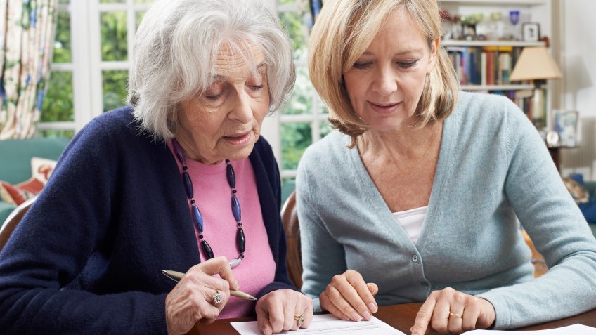 Female Neighbor Helping Senior Woman To Complete Form