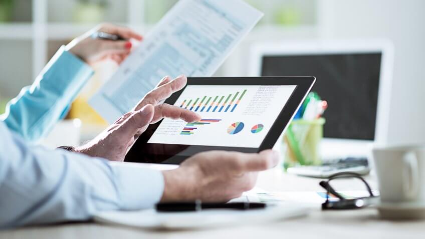 Two business people in office working on business reports, financial statements and tax form 1040 filling out.