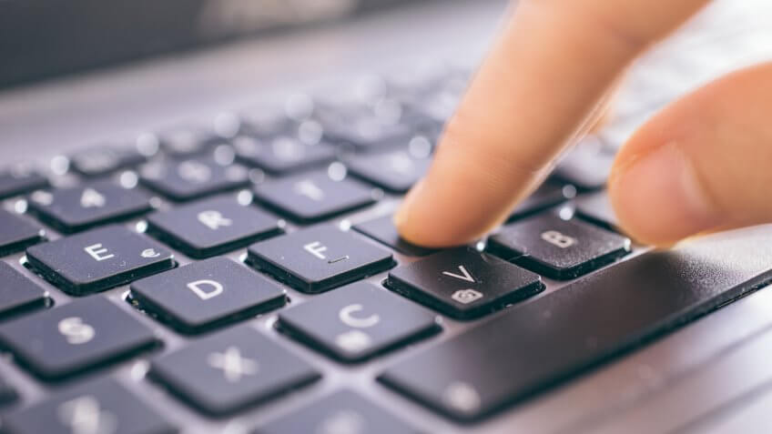 person pressing button on laptop keyboard