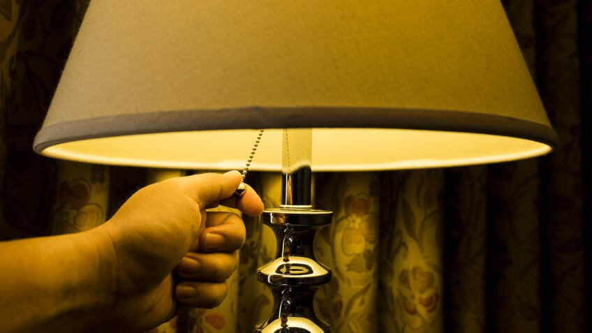 person using pull chain on lamp