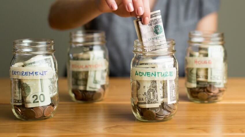 A happy woman saving in jars.
