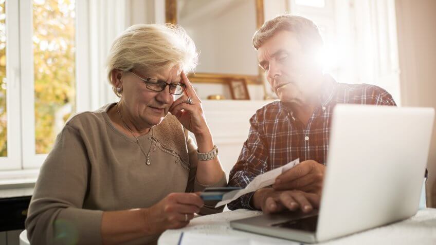 Senior couple sitting at home and having problems with paying their bills.