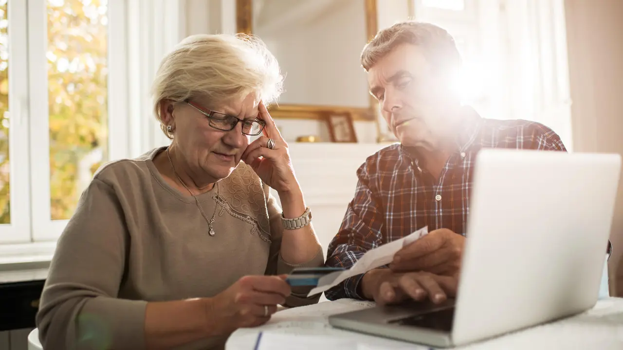 Senior couple sitting at home and having problems with paying their bills.