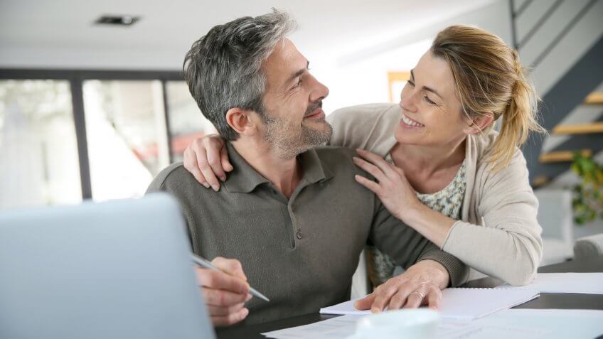 Couple calculating financial savings on internet.
