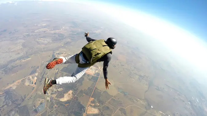 A free falling, parachuting skydiver in action, symbolizing someone taking risks.