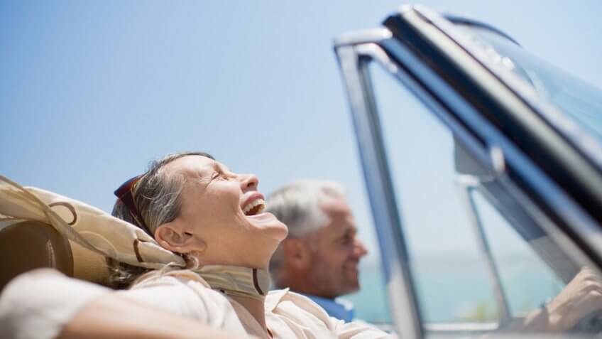 Mature couple driving in convertible.