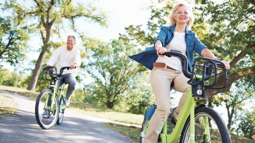 Portrait of a happy senior couple enjoying a bicycle ride in the park together.