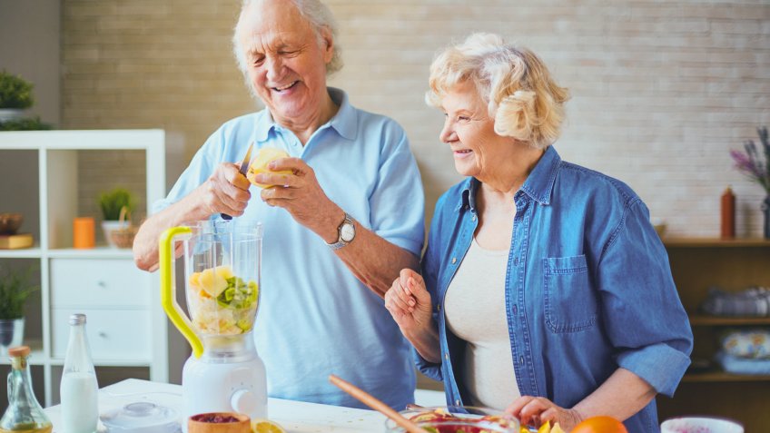 elderly couple making food with a blender