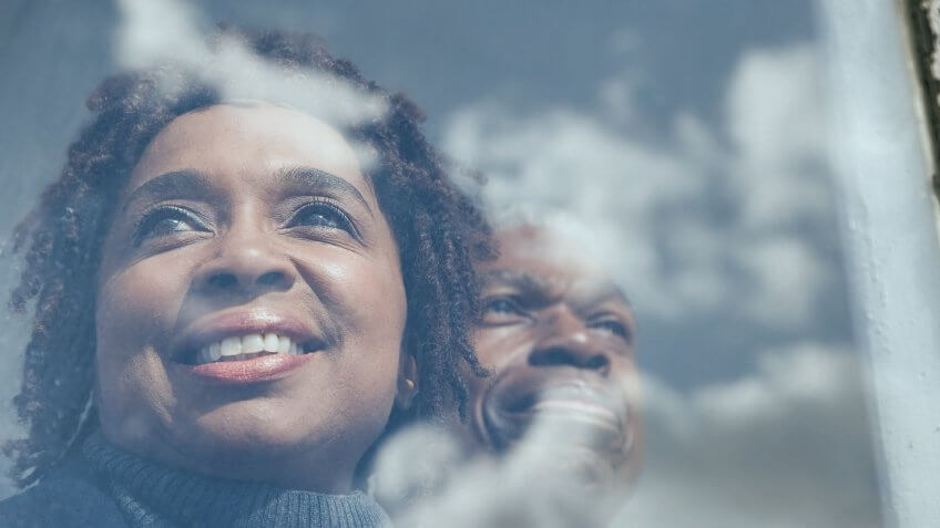 clouds reflecting on a window with a african american couple looking out