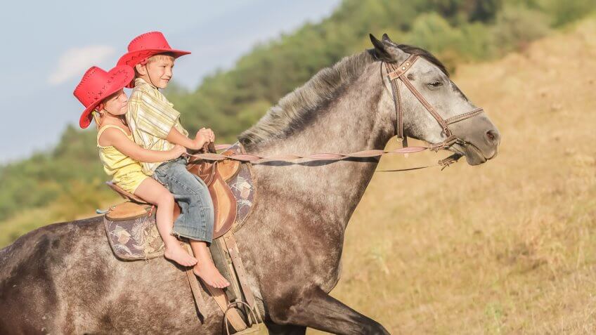 two children riding a saddled horse
