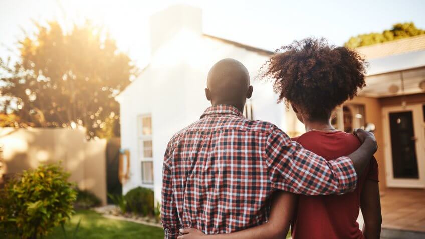 Rear view shot of a young couple admiring their new house outside.