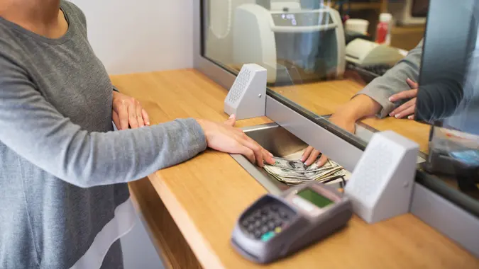 people, withdrawal, saving and finance concept - clerk giving cash money to customer at bank office or currency exchanger.