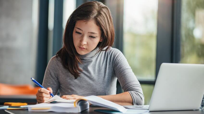 Shot of young woman taking down notes in diary.