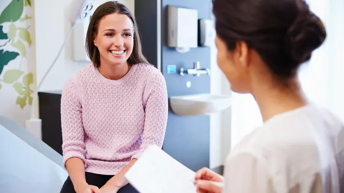 Female Patient And Doctor Have Consultation In Hospital Room.