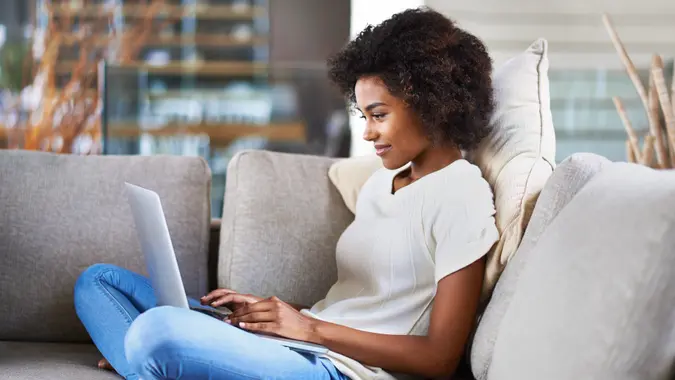 Shot of a young woman using a laptop while relaxing at homehttp://195.