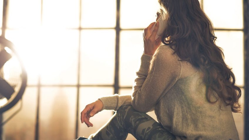 woman on the phone looking out a window