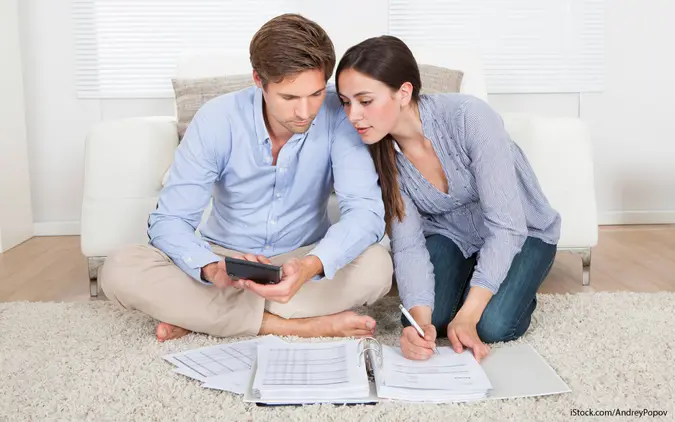 Married couple reviewing finances at home, working together to avoid debt and explore settlement options.