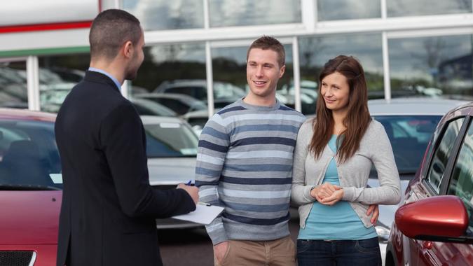 Salesman talking to a couple in a dealership.